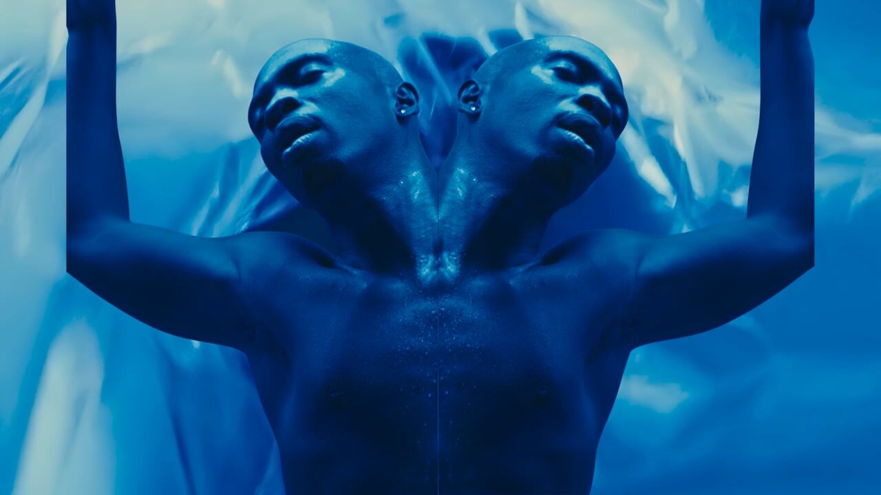 Emerge — mirrored figure against blue plastic sheeting