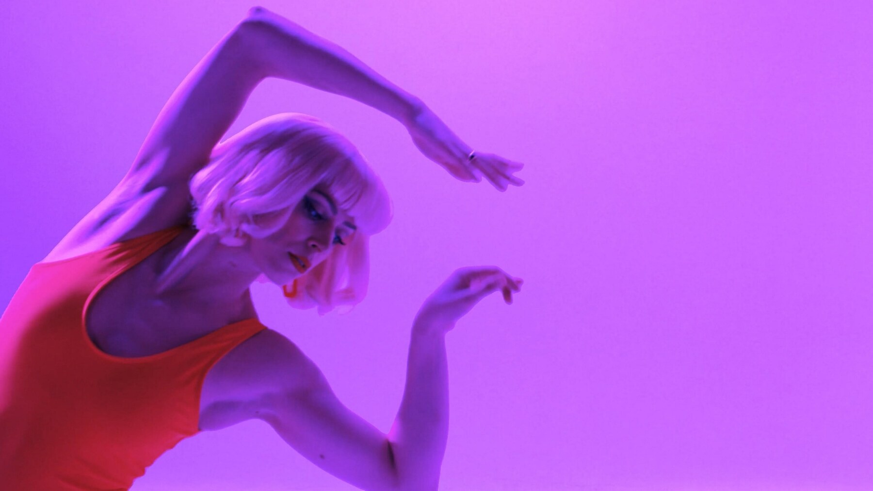Swim — dancer in a coral leotard against a pink backdrop
