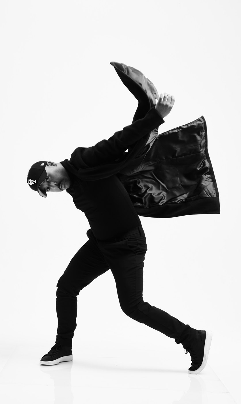 Ashley Lindsey mid-movement in an LA cap, jacket flying, black and white portrait
